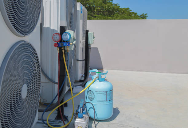 Air conditioning, HVAC service technician using gauges to check refrigerant and add refrigerant.